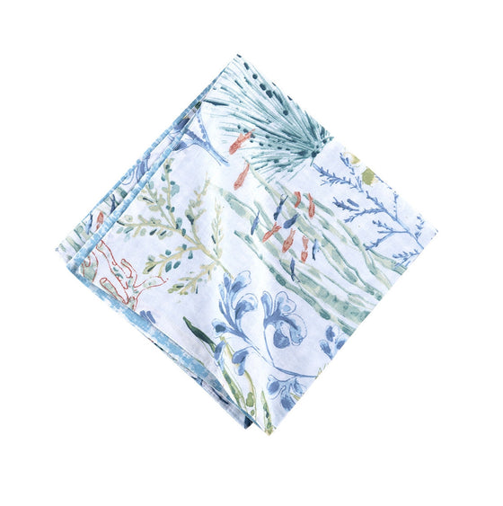 Napkin with pattern of coral, tropical fish, and shells that are light blue and green with hints of red.