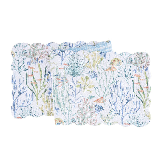 Table runner with pattern of coral, tropical fish, and shells that are light blue and green with hints of red.