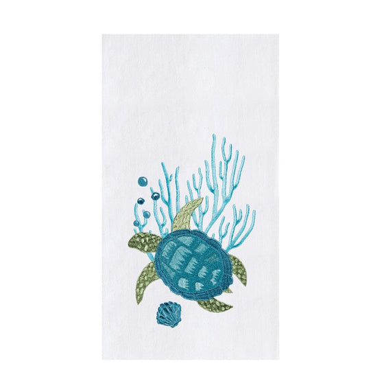 White towel with blue and green turtle next to blue coral,  a shell, and bubbles.