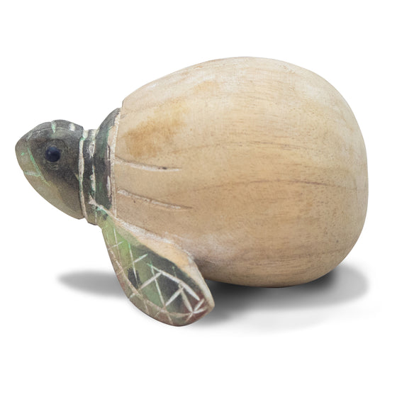 side view of a wooden green turtle partially outside of a beige egg