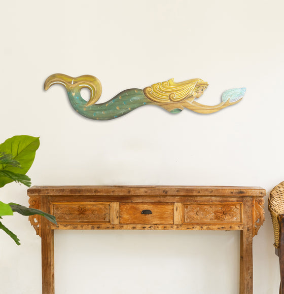 Green and yellow swimming mermaid holding a turqoise seashell hanging on the wall above a hallway table