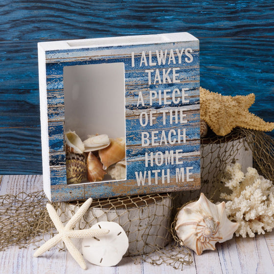 I Take A Piece Of The Beach With Me Shell Holder on a wooden  block with a crab net and other shells.