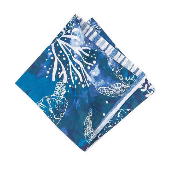 Blue napkin with white sea turtles and coral.