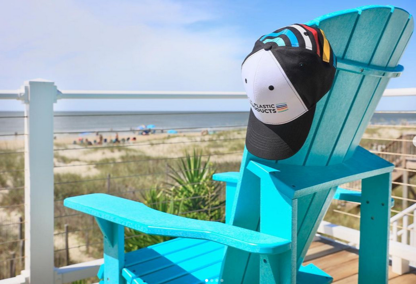  turquoise adirondack chair, with C.R. Plastics hat, on a deck overlooking the beach and ocean